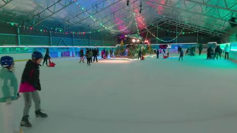Children-skating-in-an-indoor-ice-rink-around-a-festive-holiday-scene