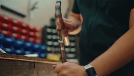 Male-hands-hammering-in-slow-motion-in-workshop-for-custom-golf-club-fitting