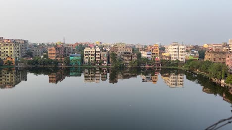 Day-view-of-a-group-of-buildings-beside-a-pond-in-Kolkata,-India