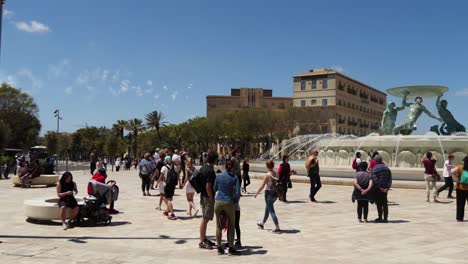 Tagsüber-Feuerwerk-Mit-Touristen,-Die-Um-Den-Tritonenbrunnen-Am-Stadttor-Von-Valletta-Herumlaufen