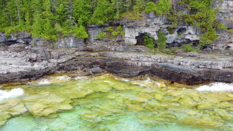 Flying-to-Cliff-Full-of-Caves-and-Lush-Green-Vegetation-on-the-Slope-Bruce-Peninsula,-Georgian-Bay