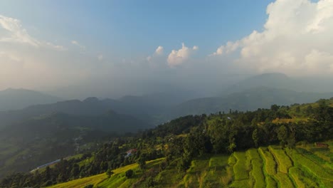 Drone-establishing-view-of-green-farmland-terraces-and-sweeping-mountain-vista-views