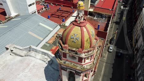 Aerial-tilt-up-shot-of-church-tower-in-Puebla-City-during-sunny-day,-México
