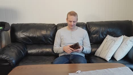 Adult-man-on-couch-breaks-down-after-discovering-his-wallet-is-empty