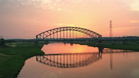 Drone-Orbit-shot-of-the-train-crossing-a-bridge-over-the-river-Rhine-near-Arnhem,-Netherlands
