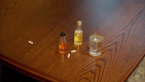 Pills-falling-down-on-wooden-table-with-alcohol,-slow-motion