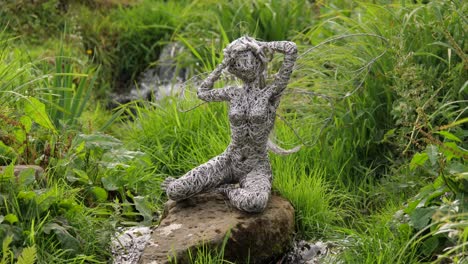 Wire-Fairy-Sitting-And-Posing-On-A-Rock-In-The-Middle-Of-A-Small-Brook