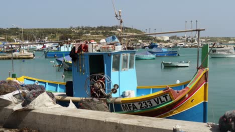Fishing-Boat-Moored-In-The-Harbor-Of-Marsaxlokk,-More-Boats-In-The-Background