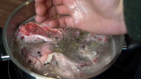Pink-rock-salt-added-to-pan-for-cooking-beef-bone-broth,-close-up-slow-motion