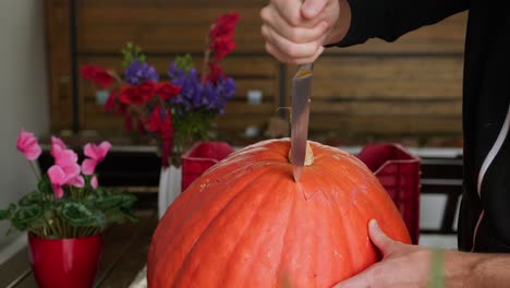 Big-pumpking-carving-for-Halloween-spooky-decoration,-cuting-top-of-with-knife,-wide-shot