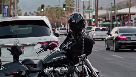 Harley-Davidson-motorcycle-parked-on-the-street-in-Palms-Springs,-California-with-cars-and-pedestrians-in-slow-motion