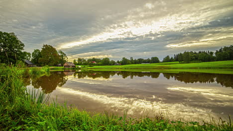 Cottage-by-a-pond-during-a-cloudscape-sunrise-time-lapse