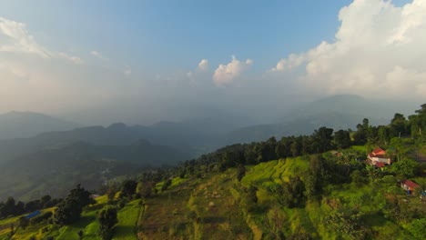 Cinematic-aerial-dolly-flyover-above-terraced-lush-vibrant-green-fields-and-mystic-mountains