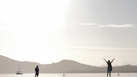 A-cinematic-tilt-down-footage-reveals-silhouettes-of-a-man-and-a-woman-on-a-pier-embracing-the-sunrise-during-meditation