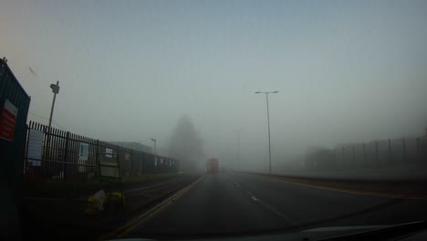 POV-Foggy-windshield-view-driving-misty-in-morning-town-traffic-roundabout-during-sunrise