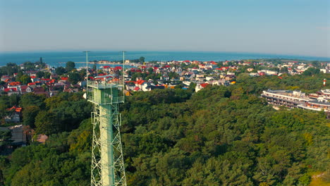 Drone-flying-above-weather-tower-in-Jastarnia,-Poland-with-baltic-sea-in-the-background
