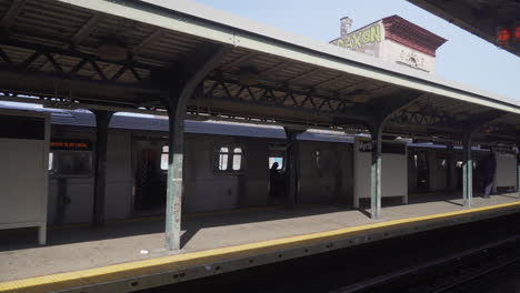 Subway-car-leaving-platform-at-outdoor-elevated-subway-Station-on-sunny-day