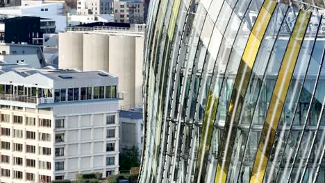 Glass-panel-detail-of-the-City-of-Wine-museum-building-and-concrete-silos-in-Bordeaux-France,-Aerial-pan-left-close-up-shot