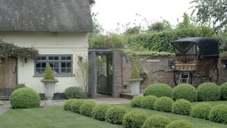 Right-pan-shot-of-an-old-english-cottage-with-a-carriage