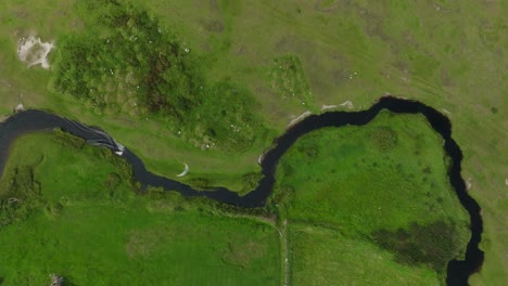 Overhead-drone-view-of-kiteboarder-navigating-winding-canal-through-lush-terrain