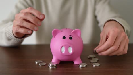 A-person-putting-a-lot-of-coins-quickly-in-the-piggy-bank