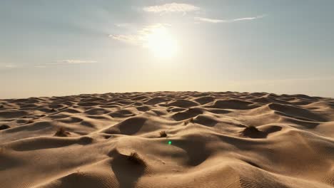 Die-Drohne-Fliegt-Vorwärts-über-Die-Sahara-Wüste,-Während-Der-Wind-An-Einem-Sonnigen-Tag-In-Tunesien-Sand-über-Die-Dünen-Bläst.-Luftaufnahmen-4k
