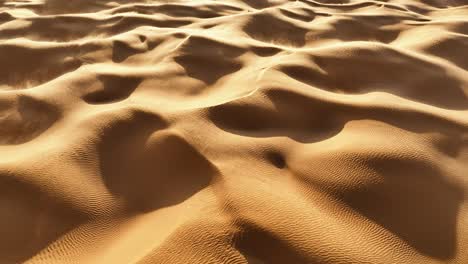 Die-Drohne-Blickt-Auf-Den-Sahara-Sand-Hinunter,-Der-Sich-Dreht,-Während-Der-Wind-Sand-über-Die-Hügel-Und-Dünen-In-Tunesien-Bläst.-Luftaufnahmen-In-4K