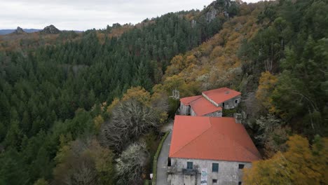 Beautiful-aerial-drone-shot-of-an-old-monastery-san-pedro-de-rocas-construction-surrounded-by-large-trees,-nature-and-mountains