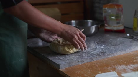 Raw-dough-mix-kneaded-by-hand-on-marble-tabletop,-filmed-as-medium-closeup-slow-motion-shot