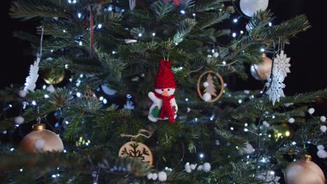 Hanging-Snowman-Decoration-on-Green-Christmas-Tree-Dark