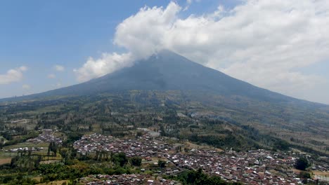 Pequeño-Pueblo-Y-Enorme-Montaña-Sumergida-En-Indonesia,-Vista-Aérea-De-Drones