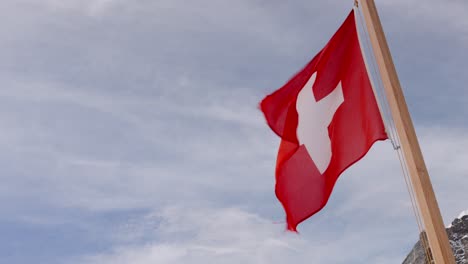 Swiss-flag-fluttering-in-the-wind,-Lauterbrunnen-valley,-Switzerland