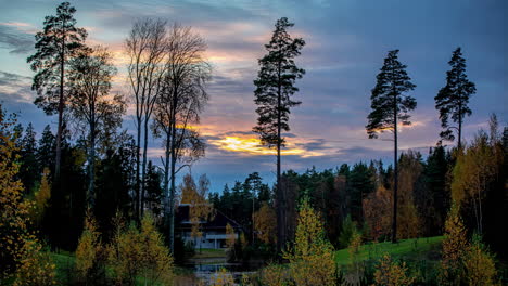 Time-lapse-wonderful-golden-hour-sunset-over-deep-forest-valley-log-cabin-in-distance