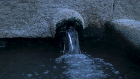 Nahaufnahme-Von-Wasser,-Das-Aus-Granit-In-Ein-Offenes-Becken-Fließt,-Statische-Aufladung