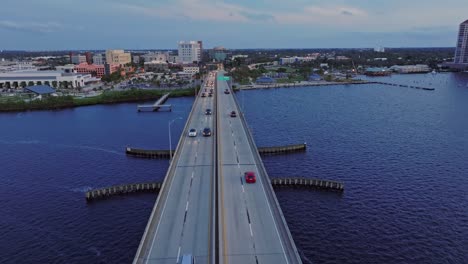Aerial-tracking-shot-of-driving-cars-on-bridge-crossing-Caloosahatchee-River-at-dusk---Fort-Myers,-Florida,-USA