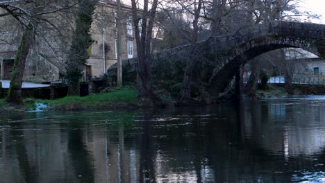 Reflection-of-Banos-de-Molgas-city-in-river-with-Roman-bridge