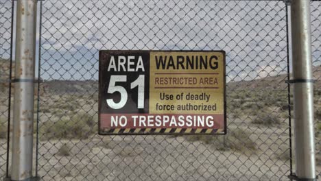 High-quality-3D-CGI-render-with-a-smooth-dollying-in-shot-of-a-chainlink-fence-at-a-secret-military-installation-in-a-desert-scene,-with-an-Area-51-Warning-Restricted-Area-sign