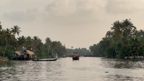 POV-Aufnahme-Viele-Boote-Fahren-Im-Wasser-Und-Es-Gibt-Viele-Kokospalmen-In-Der-Nähe-Und-Viele-Touristen-Genießen-In-Den-Booten-Die-Wunderschöne-Aufnahme-Von-Kerala