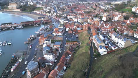 Aerial-parallax-shot-of-the-beautiful-city-of-Scarborough-North-Yorkshire-beside-a-harbor-with-boats-during-daytime-in-England
