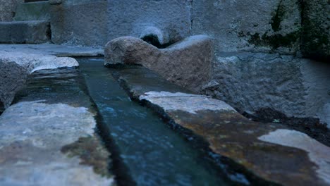 Boiling-hot-water-pours-along-open-shallow-granite-rock-trench-in-Ourense-Spain