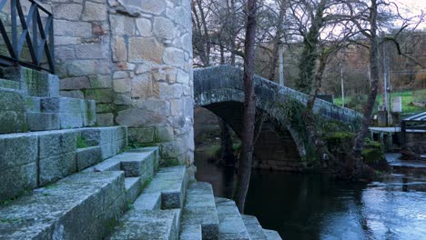 Precise-carved-stone-granite-steps-lead-to-river-Molgas-with-Roman-arched-bridge
