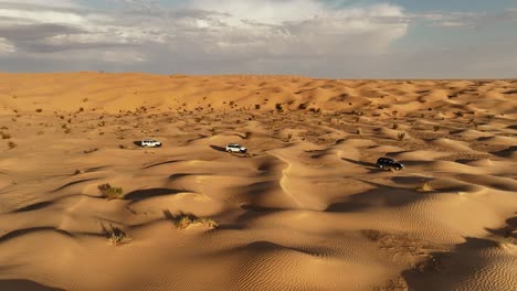 The-drone-is-flying-sideways-following-three-cars-driving-through-the-Sahara-desert-in-Tunisia-Aerial-Footage-4K