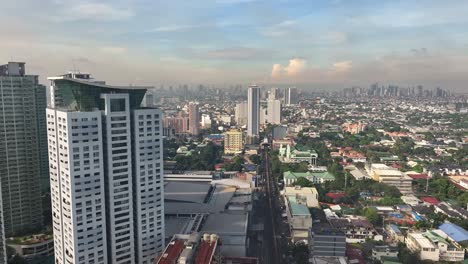 Luftflug-Entlang-Des-Turms-In-Einem-Vorort-Von-Manila-City-Und-Der-Skyline-Im-Hintergrund---Dunkelgrauer-Rauch,-Der-Am-Himmel-Fliegt