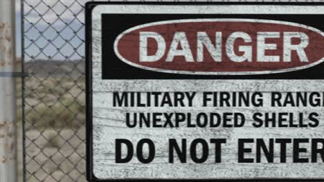 High-quality-3D-CGI-render-of-a-chainlink-fence-at-a-high-security-installation-in-a-desert-scene,-with-a-Danger-Military-Firing-Range-sign