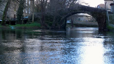 Water-shimmers-as-it-flows-and-light-reflects-bright-off-it-fronting-roman-bridge