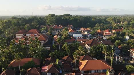 Villas-surrounded-by-dense-palm-trees-in-cultural-town-of-Ubud-during-sunrise-with-Monkey-forest-at-he-background-filmed-in-Bali,-Indonesia
