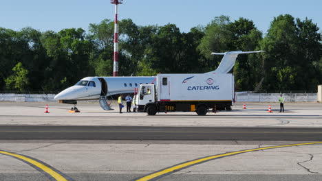 Catering-truck-arriving-to-business-jet-parked-at-Chisinau-Airport,-static