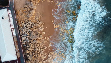Aerial-footage-capturing-the-unyielding-force-of-sea-waves-crashing-against-the-rugged-coastal-expanse-of-Portugal