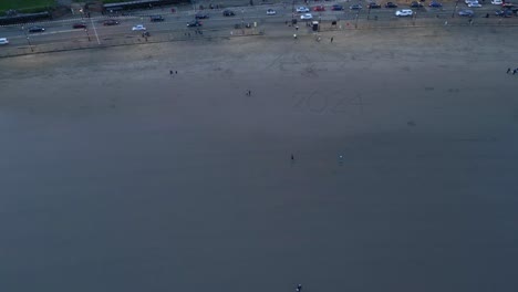Aerial-shot-of-a-beach-beside-a-busy-road-in-Scarborough-North-Yorkshire-during-sunset-in-England