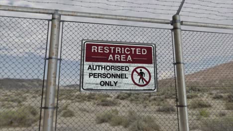 High-quality-3D-CGI-render-with-a-smooth-dollying-out-shot-of-a-chainlink-fence-at-a-high-security-installation-in-a-desert-scene,-with-a-Restricted-Area---Authorised-Personnel-Only-sign